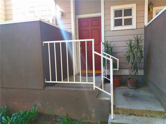 Front entry view of a house with a red door and white railing.