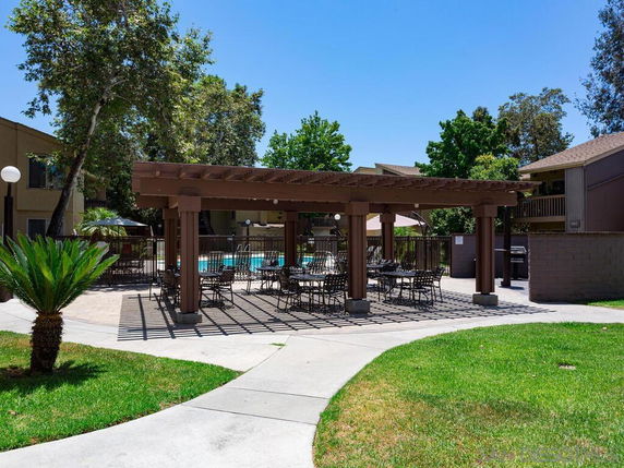 Outdoor swimming pool area with seating under a pergola.