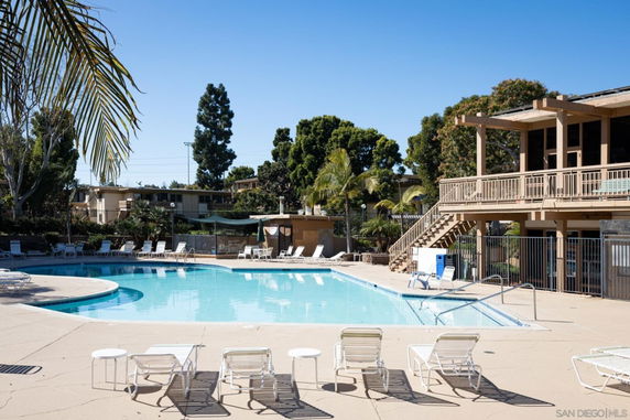 Outdoor swimming pool area with lounge chairs and surrounding trees.