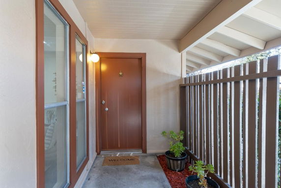 Entrance of a house with a wooden door and a welcome mat.