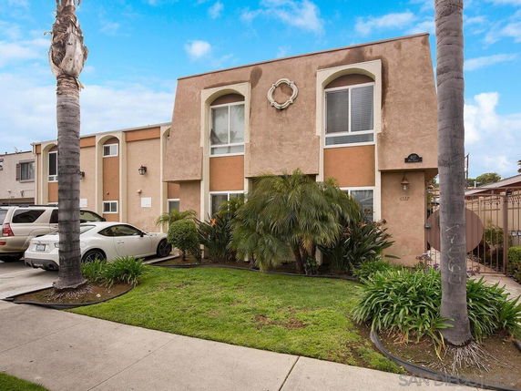 Front view of a two-story residential building with a beige facade and large windows.