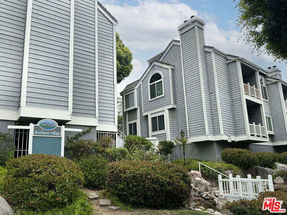 Front view of large multi-story residential buildings with gray siding and multiple balconies.