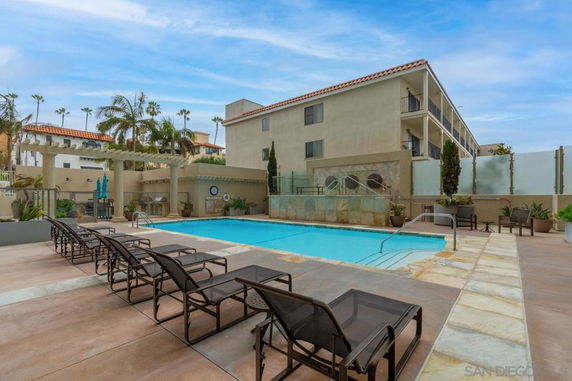 Outdoor swimming pool area with lounge chairs and adjacent building.