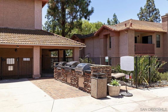 Front view of a house with a tiled roof and a patio area equipped with outdoor grills.
