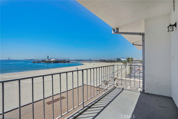 View from a balcony overlooking a sandy beach and ocean.