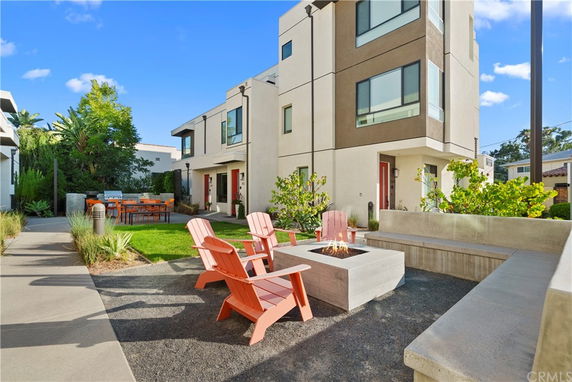 Front view of a modern multi-story house with outdoor seating area.