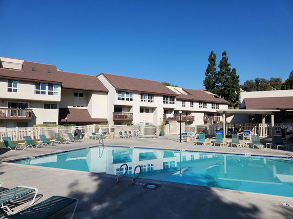 Outdoor swimming pool area in front of a multi-story residential building.