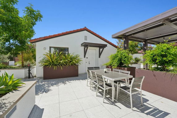 Front view of a single-story house with a red tile roof and outdoor dining area.