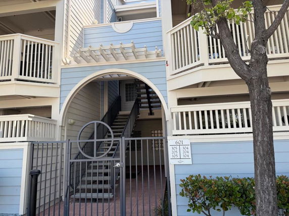 Front view of a multi-story building with balconies and an arched entrance.