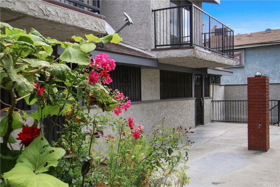 Front view of a multi-story building with balconies and a garden.