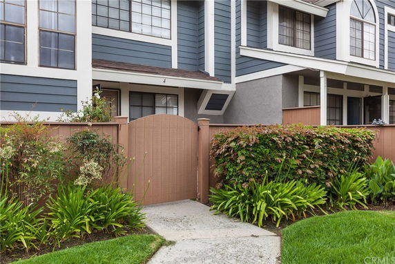 Front view of a two-story townhouse with a wooden fence and gate.