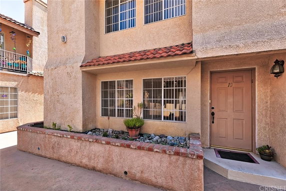 Front view of a townhouse with a small garden area and tiled roof accents.