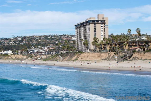 View of a beachfront area with a tall building and houses nearby.