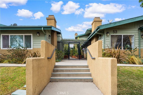 Front view of a one-story house with a gated entrance and steps leading up.