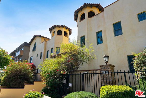Front view of a multi-story house with tower-like features and a gated entrance.