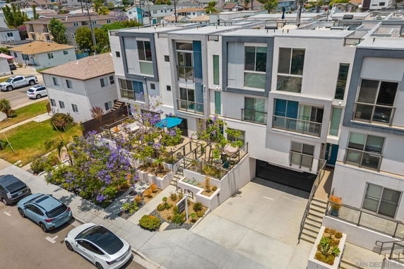 Front view of a multi-story apartment building with balconies and a landscaped entrance.