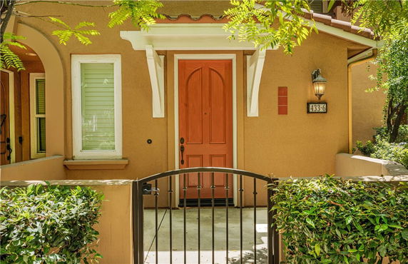 Front view of a house with an arched red door and a gated entrance.