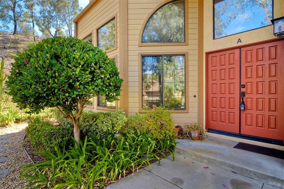 Front view of a house with a distinctive yellow facade and red double doors.