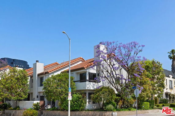 Front view of a two-story house with a sloping roof and chimney.