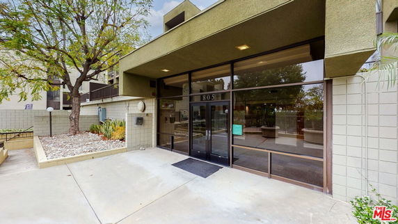 Front view of a building entrance with large glass doors and concrete pathway.