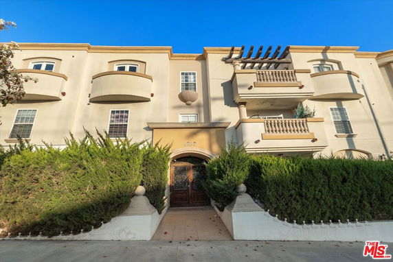 Front view of a multi-story residential building with balconies and decorative elements.