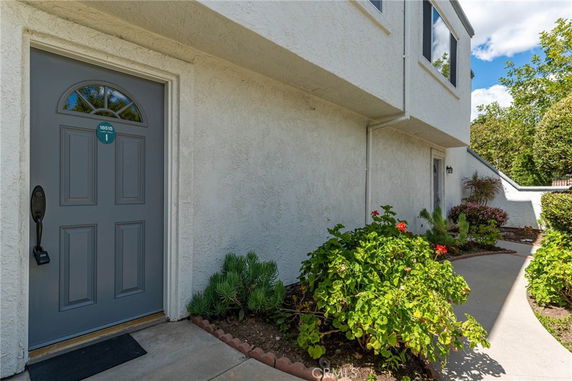 Front view of a house with a gray door and surrounding walkway.