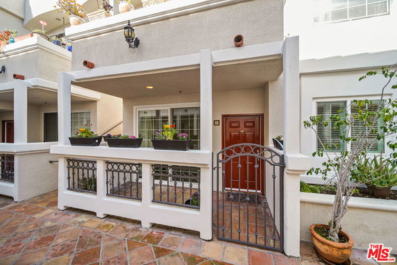 Front view of a two-story building with a gated entrance and potted plants.