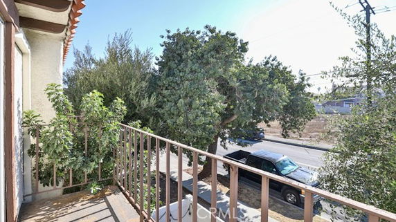 View from a building showing trees and a parked vehicle on the street nearby.