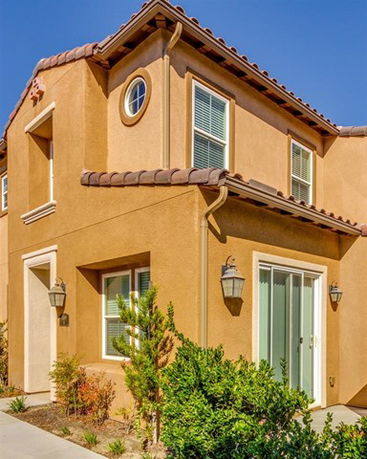 Front view of a two-story house with a brown exterior and tile roof.