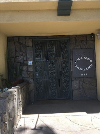Front view of a building entrance with stone walls and a decorative metal gate.