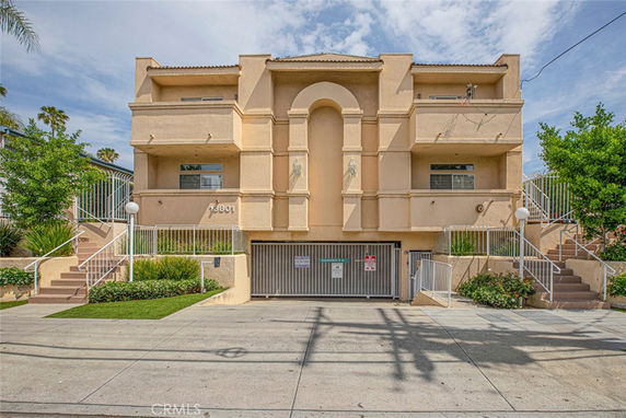 Front view of a multi-story building with balconies and a gated entrance.