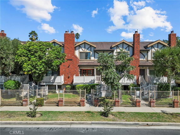 Front view of a multi-story building with brick chimneys and a gated entrance.