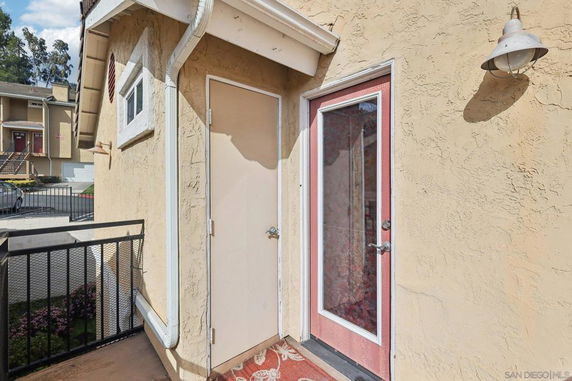 Outdoor view of a building's side entrance with textured walls and decorative trim.