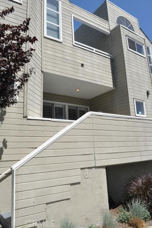 Front view of a multi-story house with beige siding and a staircase leading to the entrance.