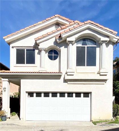 Front view of a two-story house with a prominent garage and arched windows.