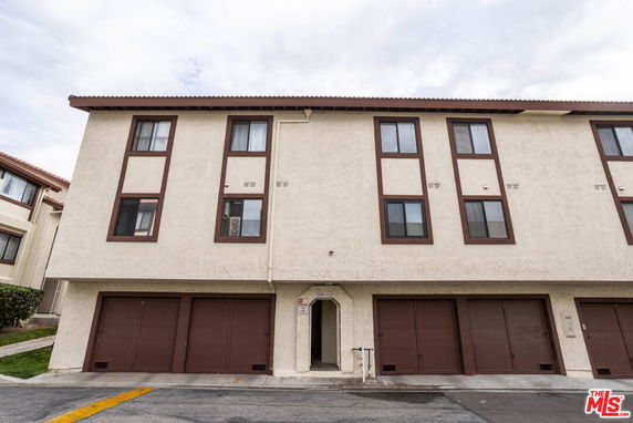 Front view of a multi-story building with brown trim and multiple garages.