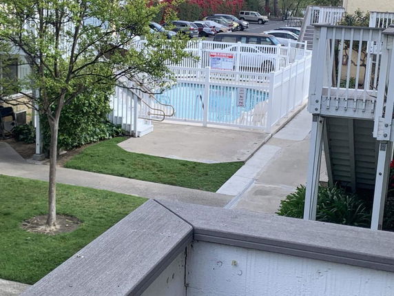 Outdoor view of a fenced swimming pool area within a residential complex.