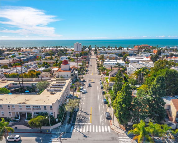 Aerial view of a coastal city with streets, buildings, and ocean in the background.