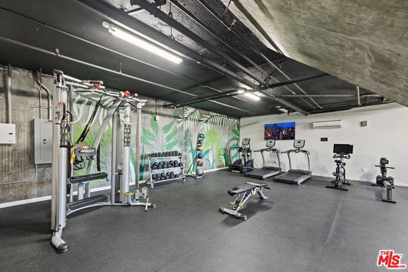 Indoor gym area with exercise equipment including treadmills, weight machines, and a mural on the wall.