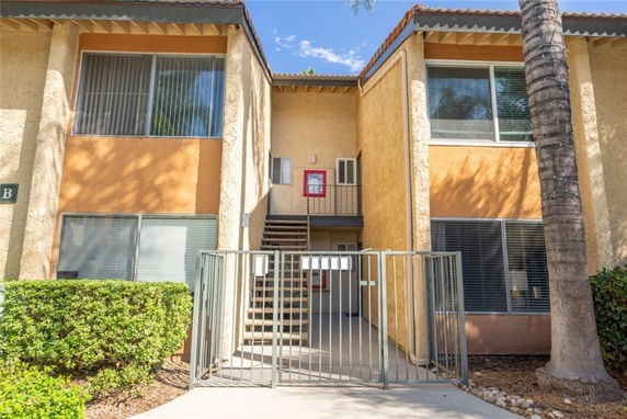 Front view of a two-story apartment building with gated entrance and large windows.