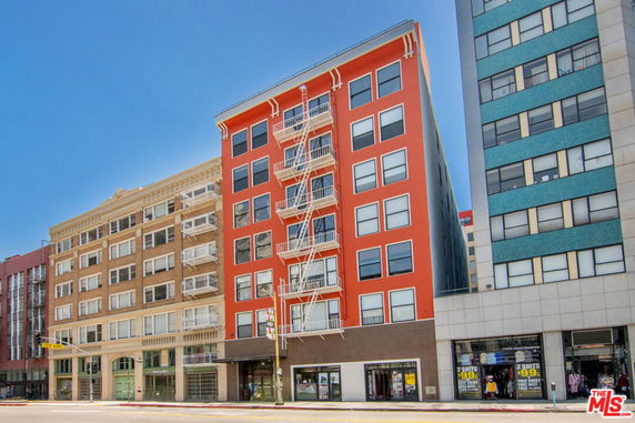 Front view of multi-story buildings with fire escapes and store fronts.