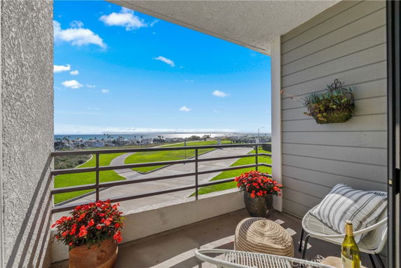 View of surrounding areas seen from a balcony, overlooking green space and the ocean.
