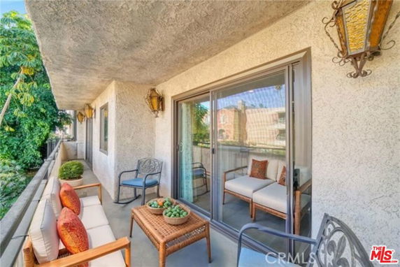 Outdoor balcony with seating area and view of adjacent buildings.