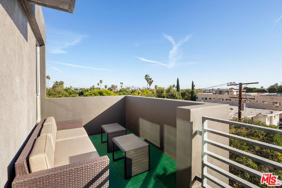 Outdoor seating area on a rooftop with views of surrounding greenery and cityscape.