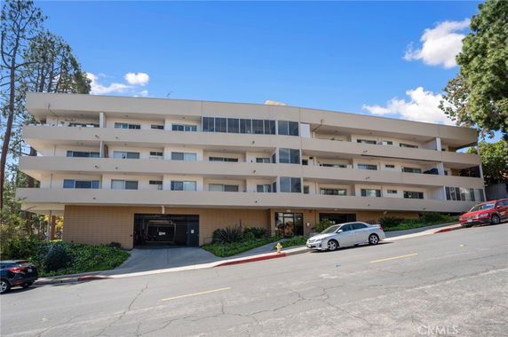 Front view of a multi-story apartment building with a sloped driveway.