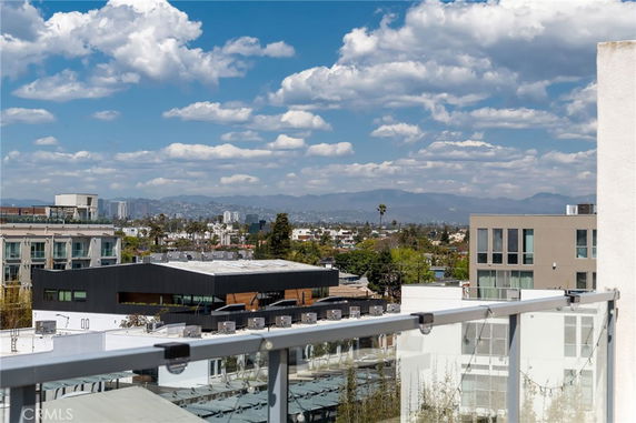 Panoramic view from a rooftop showing buildings and distant mountains.