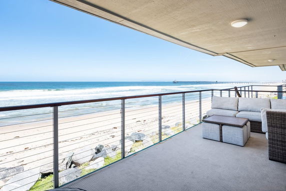 Balcony view of ocean and beach with a seating area.