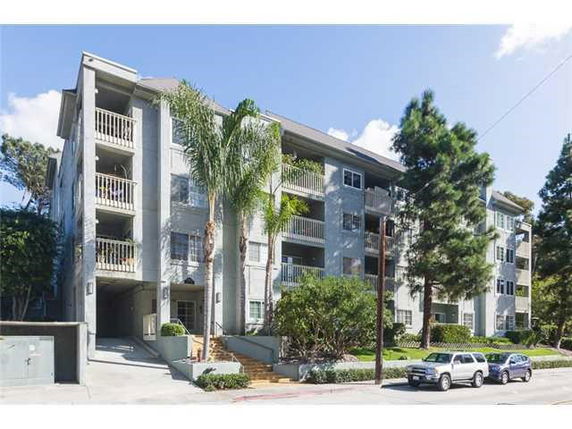Front view of a multi-story apartment building with balconies and a driveway.
