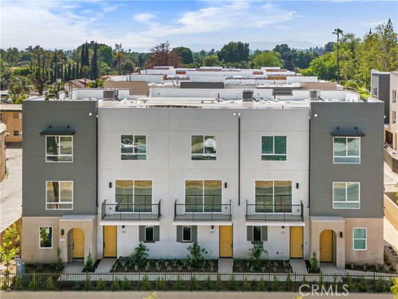 Front view of a modern townhouse building with three levels and balconies.