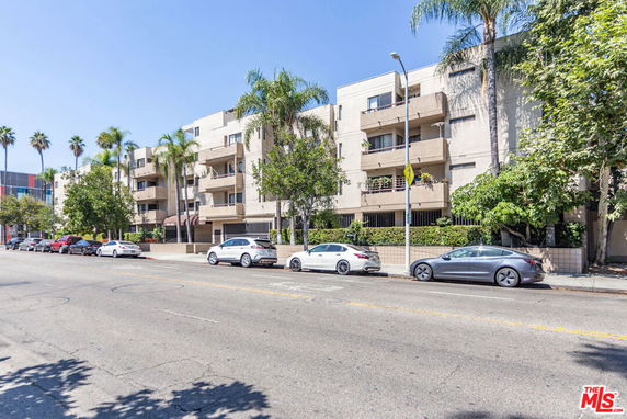 Front view of a multi-story building with balconies and palm trees.